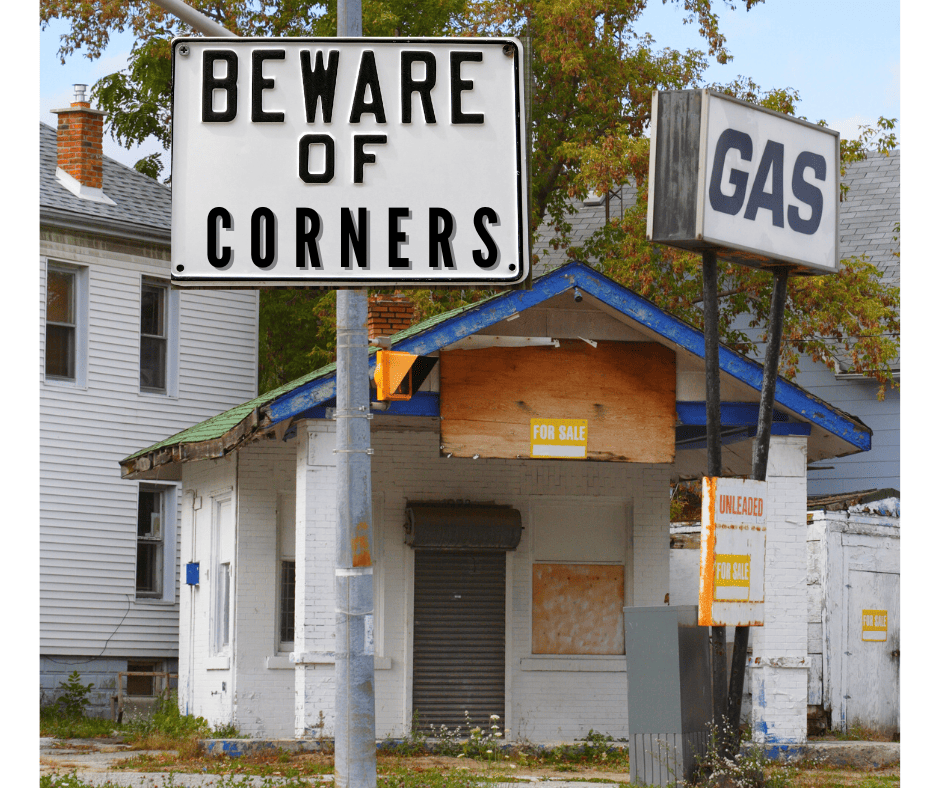 Signs reading "Beware of Corners" and "Gas" stand in front of an abandoned gas station.